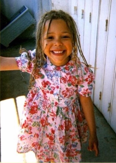 A young Tiffany in a pink flowery dress smiling